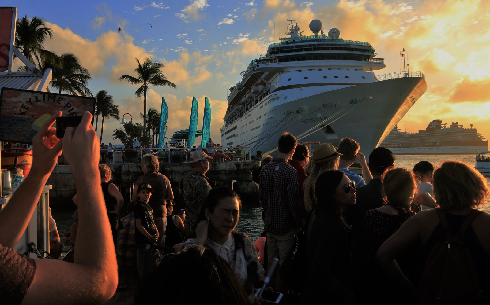 People in front of a cruise ship in the evening light.